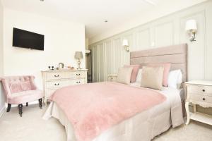 a white bedroom with a pink bed and a chair at Chequers Inn in Harrogate