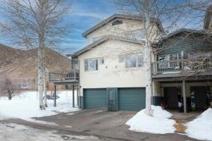 a white house with a green garage in the snow at Greenbrier Townhouse #25 in Avon