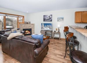 a living room with a leather couch and a fireplace at Greenbrier Townhouse #25 in Avon