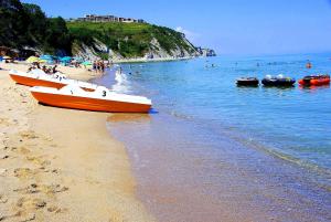 an orange boat on a beach with people in the water at Апартамент Деа - Apartment Dea in Byala +43 photos