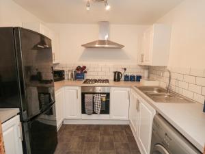 a kitchen with white cabinets and a black refrigerator at Psalm Cottage in Scarborough +19 photos