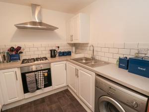 a kitchen with white cabinets and a sink and a dishwasher at Psalm Cottage in Scarborough
