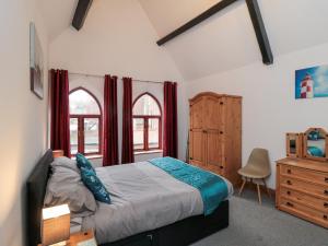 a bedroom with a bed and a dresser and two windows at Psalm Cottage in Scarborough