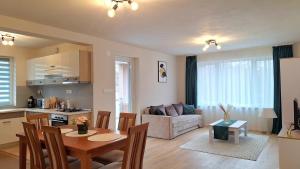 a kitchen and a living room with a table and chairs at Lotus Apartman III in Odorheiu Secuiesc