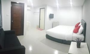 a white bedroom with a bed and a black chair at The Clover Lampang in Lampang