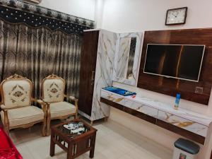 a living room with two chairs and a tv at Hotel Royal Residency in Karachi