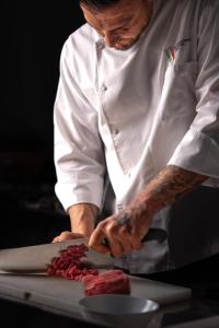 a chef cutting meat on top of a cutting board at Best Western Plus Sabaudia Hotel in Sabaudia