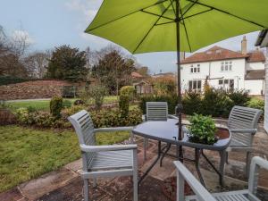 ein Tisch und Stühle mit einem grünen Sonnenschirm in der Unterkunft Ellesmere Cottage in Hornsea