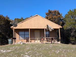 a house with a picnic table in front of it at Cedarvale Cabins Turner Falls in Davis