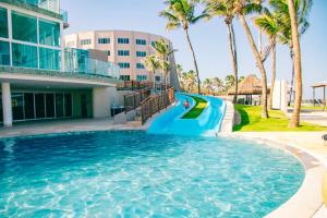 a slide in a swimming pool at a resort with palm trees at Costeira Palace Beach Resort All Inclusive in Natal