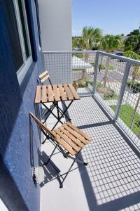 a balcony with two wooden chairs and a fence at Ivory at Aviara East Pompano in Pompano Beach