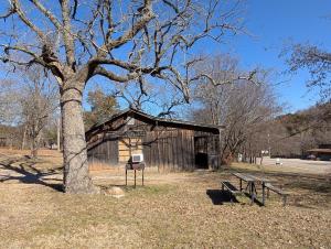 an old shed with a tree and benches in a park at Cedarvale Cabins Turner Falls in Davis