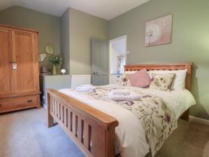 ein Schlafzimmer mit einem großen Bett mit einem hölzernen Kopfteil in der Unterkunft Daisy Cottage in Matlock