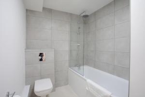 a white bathroom with a tub and a toilet at 2BR, smart TV, self check-in, coffee machine in Manchester +8 photos