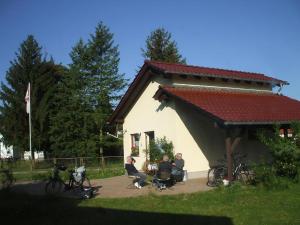 a group of people sitting in front of a building at Ferienhaus In Kienitz Mit Grill, Terrasse Und Garten in Letschin