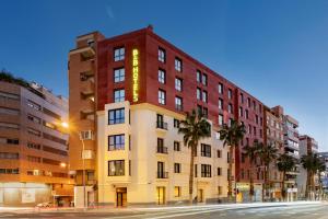 阿利坎特B&B HOTEL Alicante Centro的一条棕榈树街道上的建筑