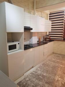 a kitchen with white cabinets and a microwave at Sukhrob PLS in Samarkand