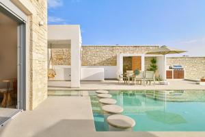 a swimming pool with stools in a house at Aegean Sunset Villas & Spa 'Villa Sea' in Skouloúfia +46 photos