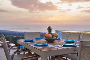 a wooden table with a bowl of fruit on it at Aegean Sunset Villas & Spa 'Villa Sea' in Skouloúfia