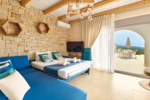 a bedroom with a blue couch and a stone wall at Aegean Sunset Villas & Spa 'Villa Sea' in Skouloúfia