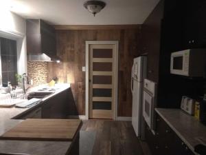 a kitchen with wooden walls and a white refrigerator at Paradise Eastern Township cottage in Cowansville +15 photos