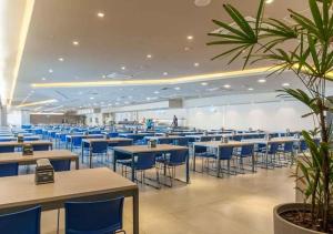 a cafeteria with tables and blue chairs and people at SOLAR DAS AGUAS PARQUE RESORT in Olímpia