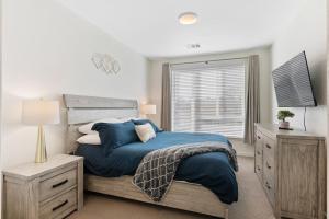 a bedroom with a bed with blue sheets and a window at My Sweet Rentals- 30 night min in Aurora +30 photos