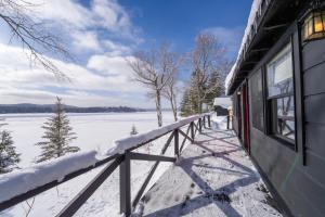 una veranda coperta da neve di una casa con vista sul lago di Great Pines a Old Forge