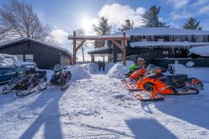 tre moto parcheggiate nella neve di fronte a un edificio di Great Pines a Old Forge