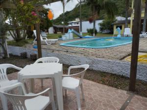 a table and chairs in front of a pool at Pousada BELEZAS DE LAGUNA in Laguna
