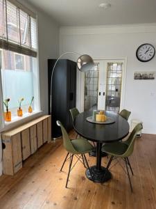 a dining room table with chairs and a clock on the wall at Appartement aan het water in Alkmaar