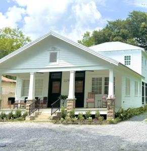 a white house with chairs on the porch at The Big Twisted Oaks in Bay Saint Louis