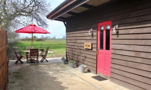 a patio with a red door and a table with an umbrella at The Little Stable in Corby