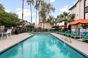 a swimming pool with chairs and umbrellas at a resort at Tempe Hideaway Luxe Amenities Parking in Tempe