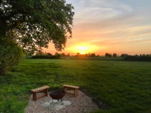 a grill and bench in a field at sunset at The Little Stable in Corby +8 photos