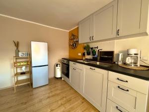 a kitchen with white cabinets and a white refrigerator at Appartment mit Garten im Beachhouse am Goitzschesee - strandnah & gemütlich in Bitterfeld +5 photos