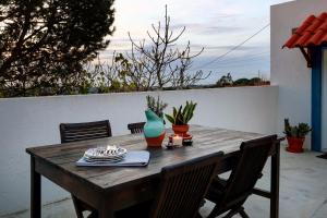 a wooden table with chairs and a blue vase at Refúgio da Alma in Mafra