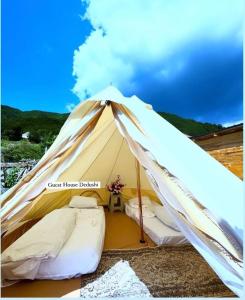a white tent with two beds in it at Dedushi camping place in Vusanje