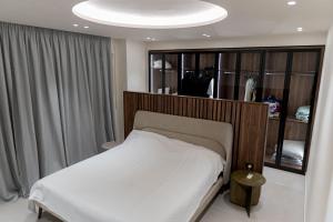 a bedroom with a white bed with a wooden headboard at Crystal Beach Radhime in Vlorë