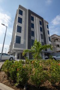 Un edificio alto con una palmera delante. en شقق الضيافة الخاصه, en Yeda