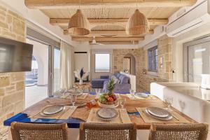 a dining room with a wooden table and chairs at Aegean Sunset Villas & Spa 'Villa Sky' in Skouloúfia