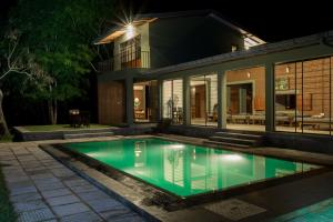 a swimming pool in front of a house at night at Neem Tree House in Kirinda