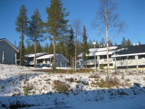 ein Gebäude mit Schnee auf dem Boden und Bäumen in der Unterkunft Kuerkaltio Holiday Village in Äkäslompolo