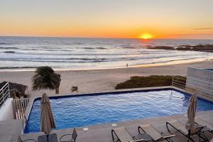 a view of a swimming pool and the beach at sunset at Condo Playa & Waterfront Heated Alberca in Mazatlán