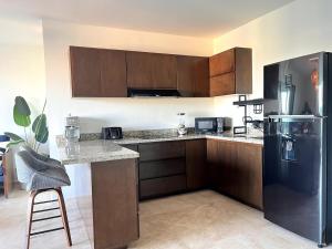 a kitchen with wooden cabinets and a black refrigerator at Condo Playa & Waterfront Heated Alberca in Mazatlán