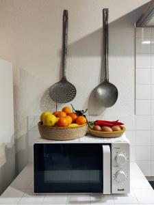 two baskets of fruit on top of a microwave at Refúgio da Alma in Mafra