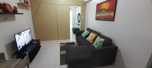 a living room with two couches and a flat screen tv at Rm Staycation TaalView Smdc in Tagaytay