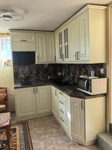 a kitchen with white cabinets and a microwave at Вила Езерото in Lipnik
