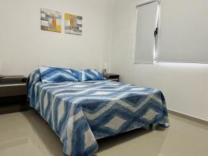 a bedroom with a bed with a blue and white blanket at Alojamiento Puerto Madryn a metros del Mar in Puerto Madryn