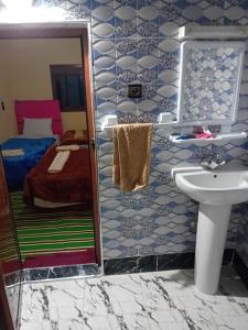 a bathroom with a sink and a bed and a mirror at Maison D'hôtes Chez Bassou Agoudal in Agoudal